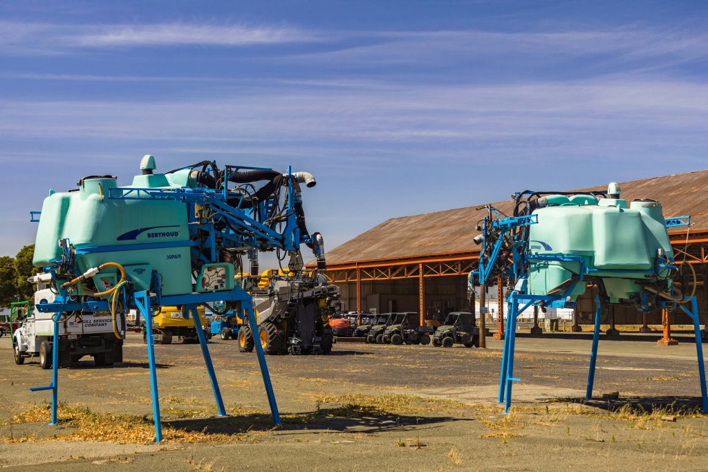 Outdoor view of large agricultural sprayers in an industrial storage yard.